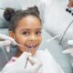 Happy afro kid on regular check up of teeth in dental clinic